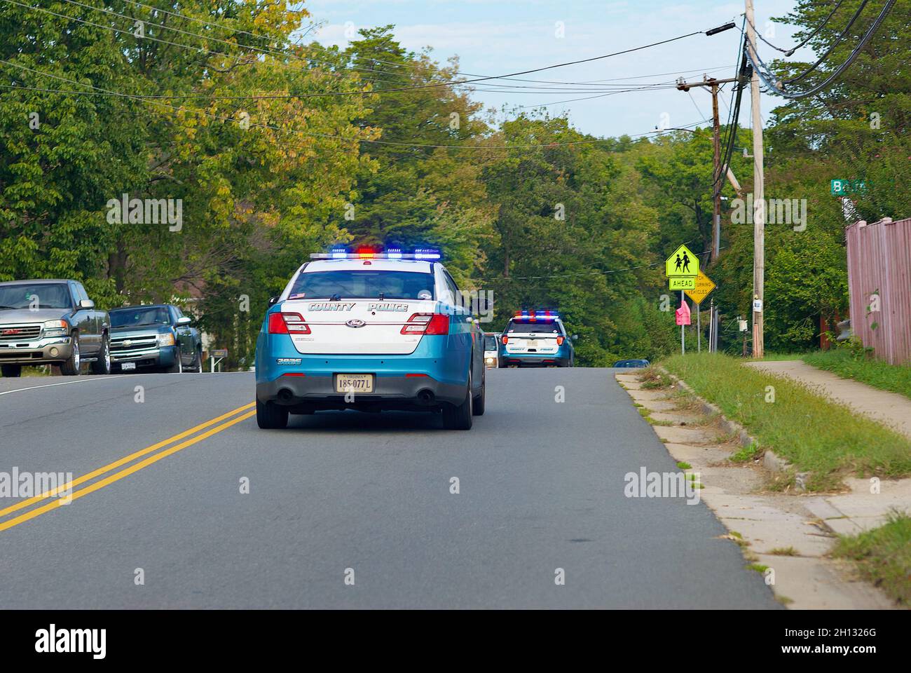 Woodbridge, Virginia, USA - October 15, 2021: Two Prince William County police cruisers speed through a neighborhood responding to a call for help. Stock Photo