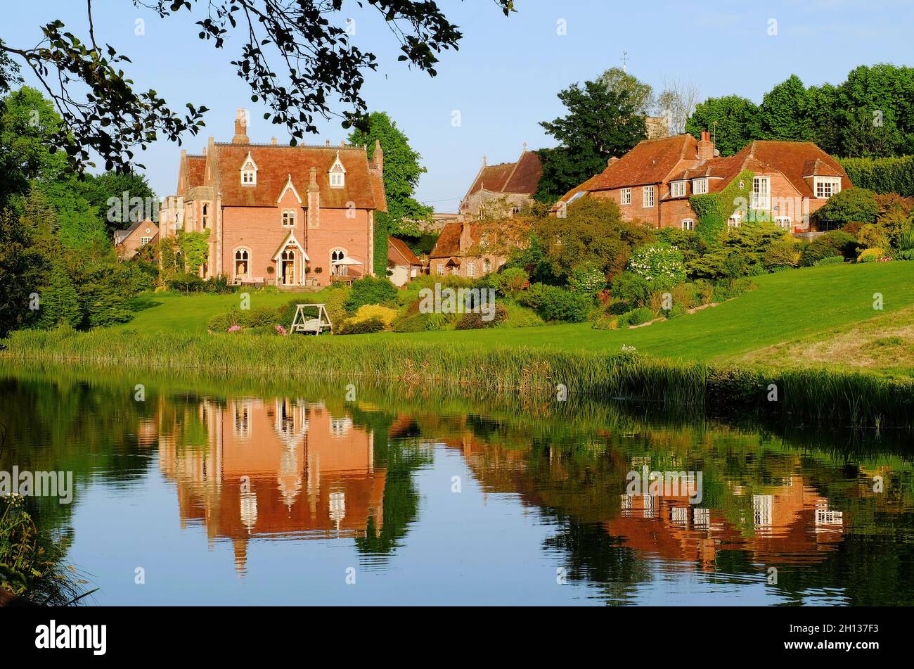 Colourful houses in Kintbury village and reflections in the Kennet and Avon Canal soon before sunset in Kintbury, Berkshire, England Stock Photo
