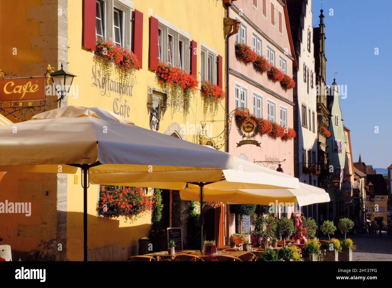 Colourful traditional buildings and outdoor cafes soon before sunset in Rothenburg ob der Tauber, Bavaria, Germany Stock Photo