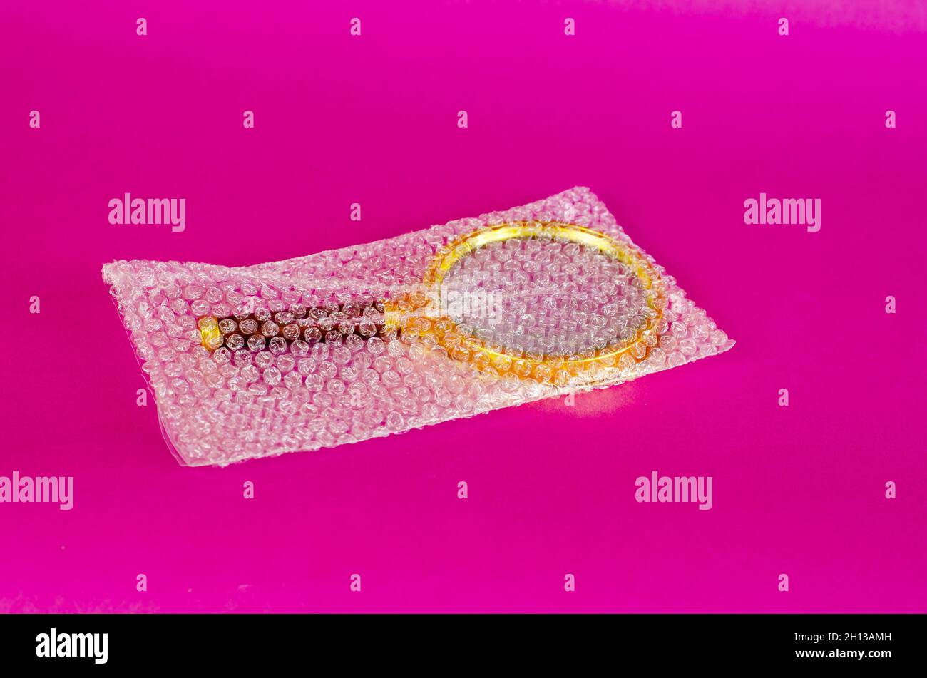 Magnifying glass and bubble wrap on pink background. Selective Focus. Stock Photo