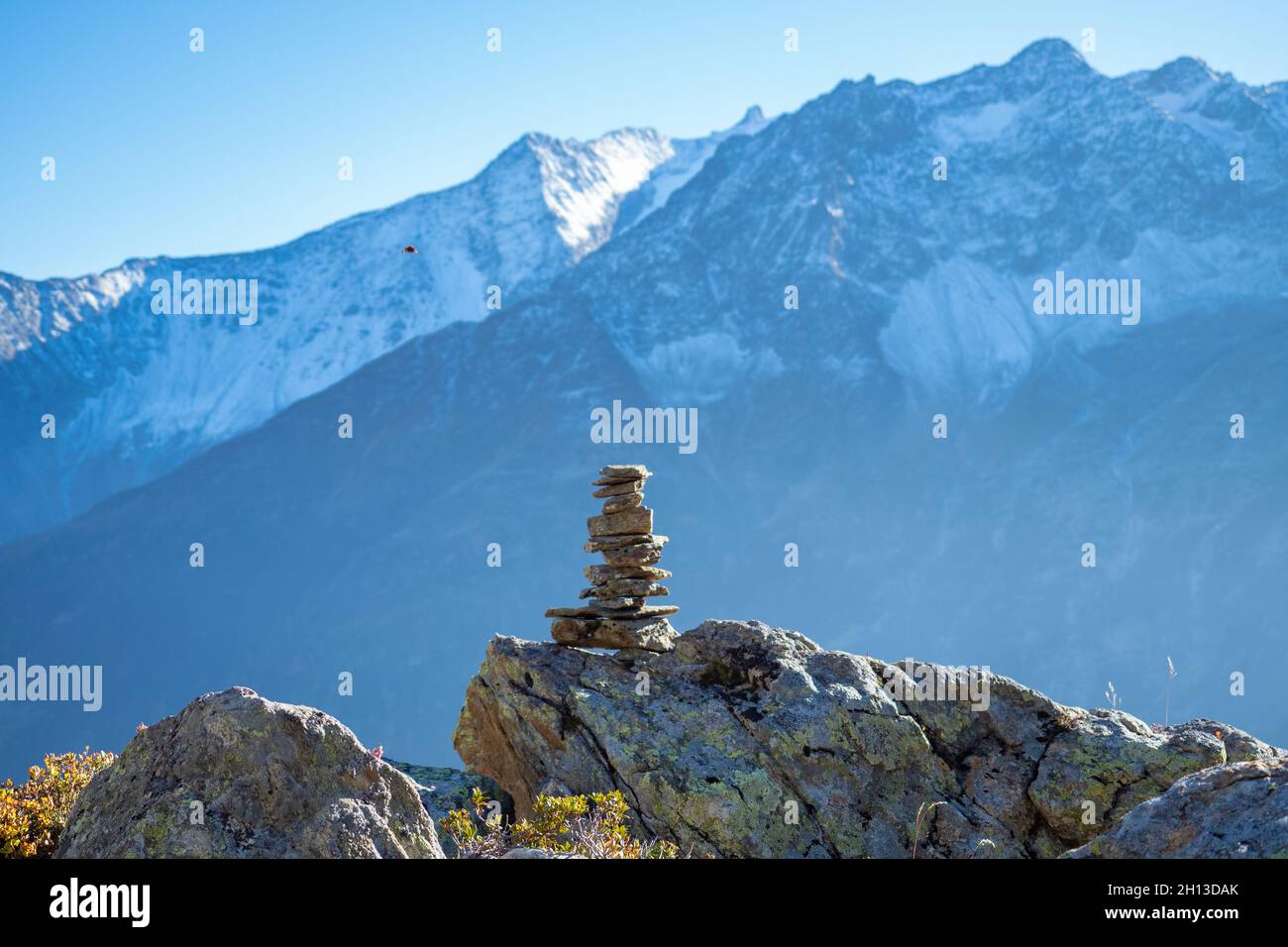 Hiking in Central Switzerland. A cairn marking a footpath, high mountains in the background Stock Photo