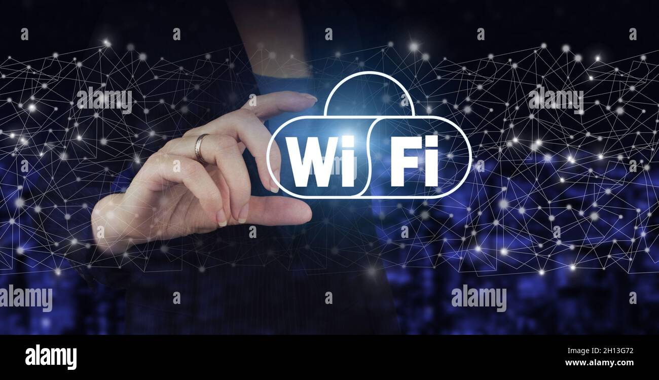 Wi Fi wireless concept. Hand hold digital hologram Wi Fi sign on city dark blurred background. Free WiFi network signal technology internet concept Stock Photo