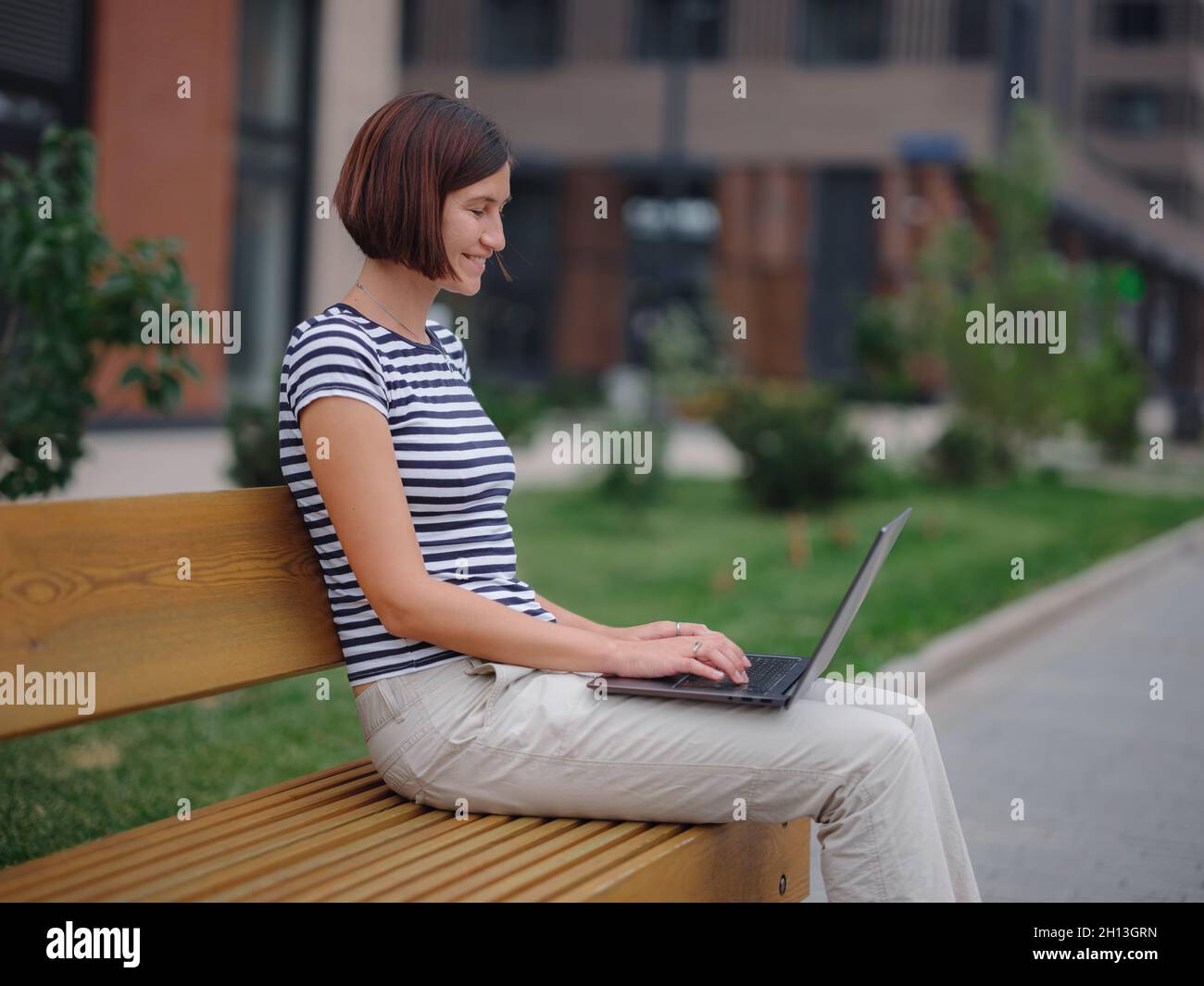 Young asian female student working at laptop sit down on bench outside ...