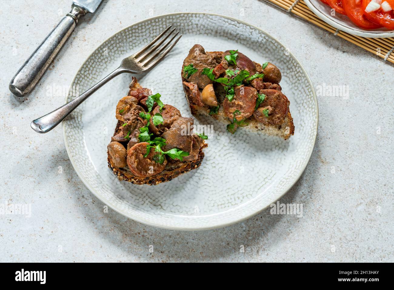 Chicken liver and chorizo open sandwich garnished with fresh parsley