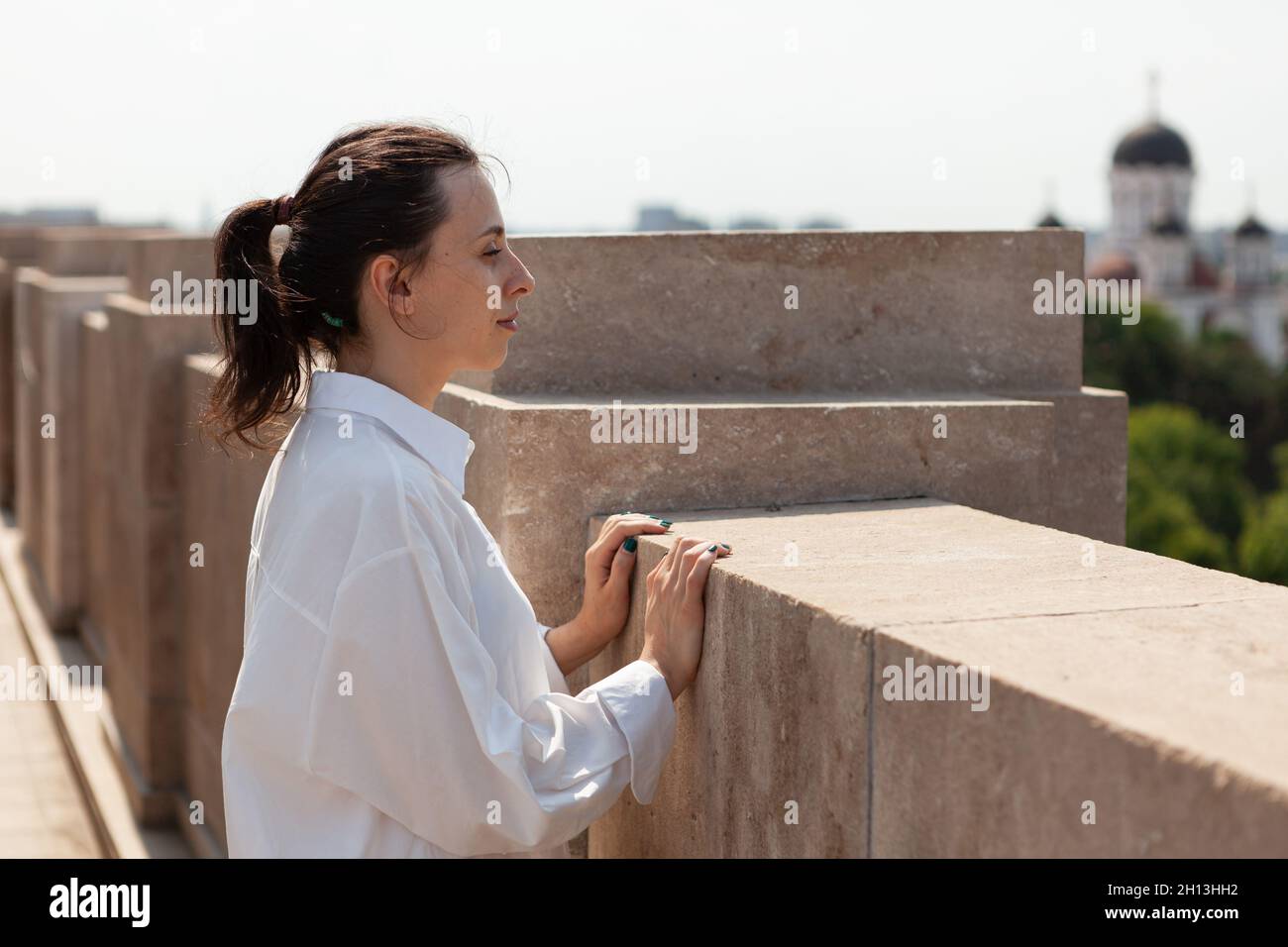 Toursit woman looking at metropolitan city from panoramic terrace of bulding tower enjoying summer vacation. View of city skyline from observation point. Panoramic view of buildings Stock Photo