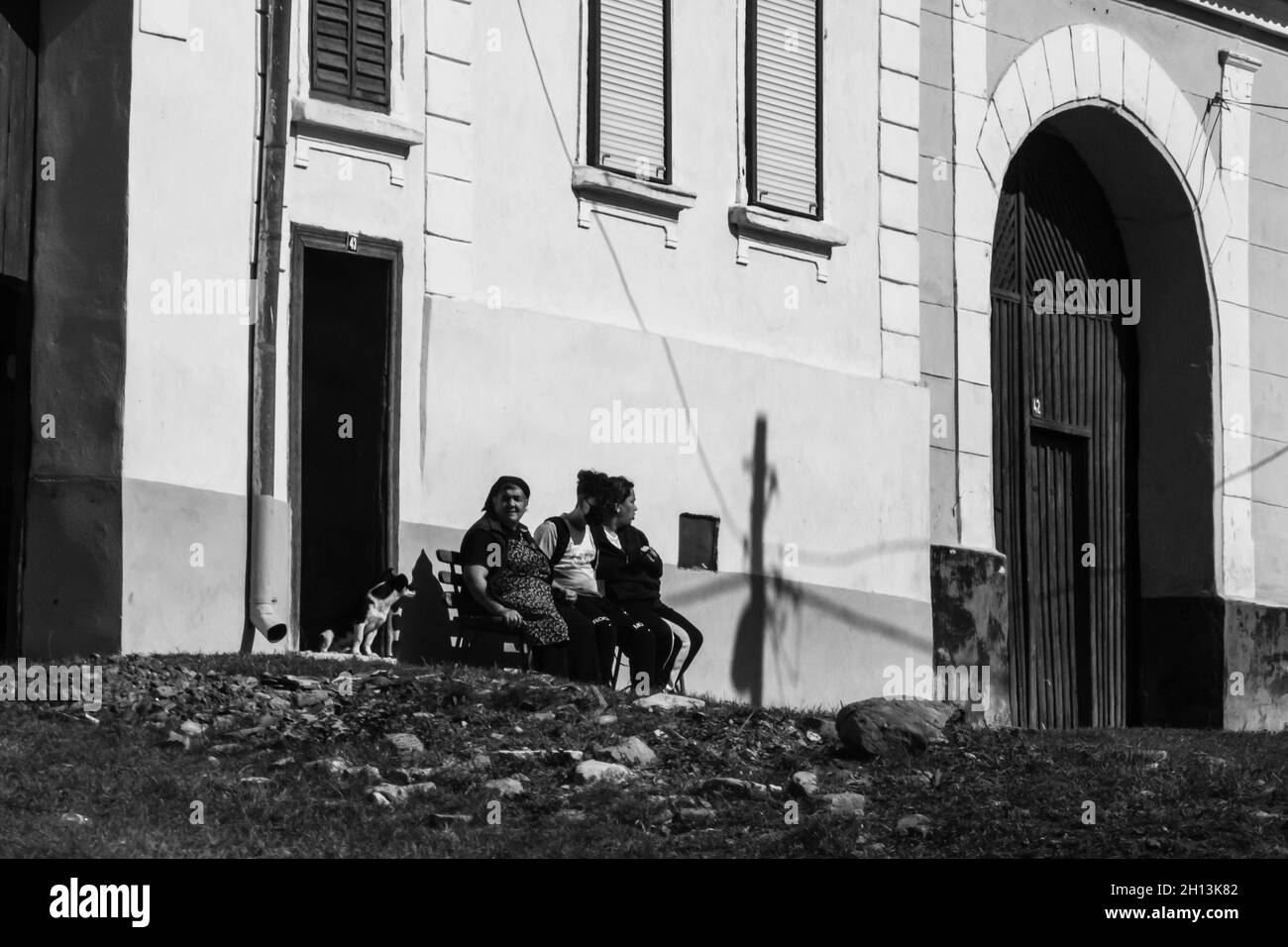 BUCHARE, ROMANIA - Sep 01, 2021: A greyscale shot of the village residents sitting near the building. Viscari, Romania Stock Photo