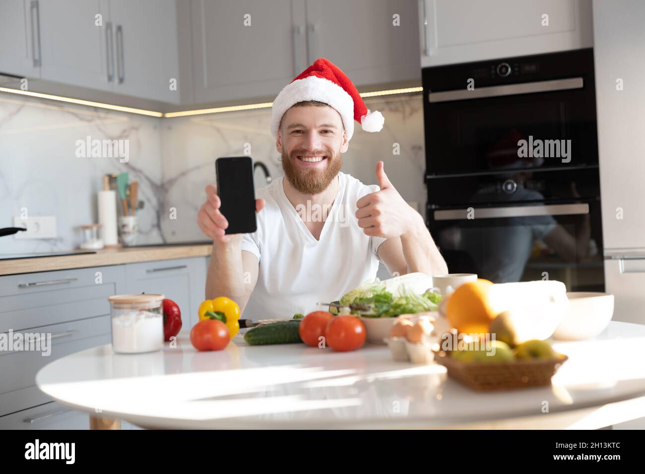 Man showing mobile phone and thumb up at table Stock Photo