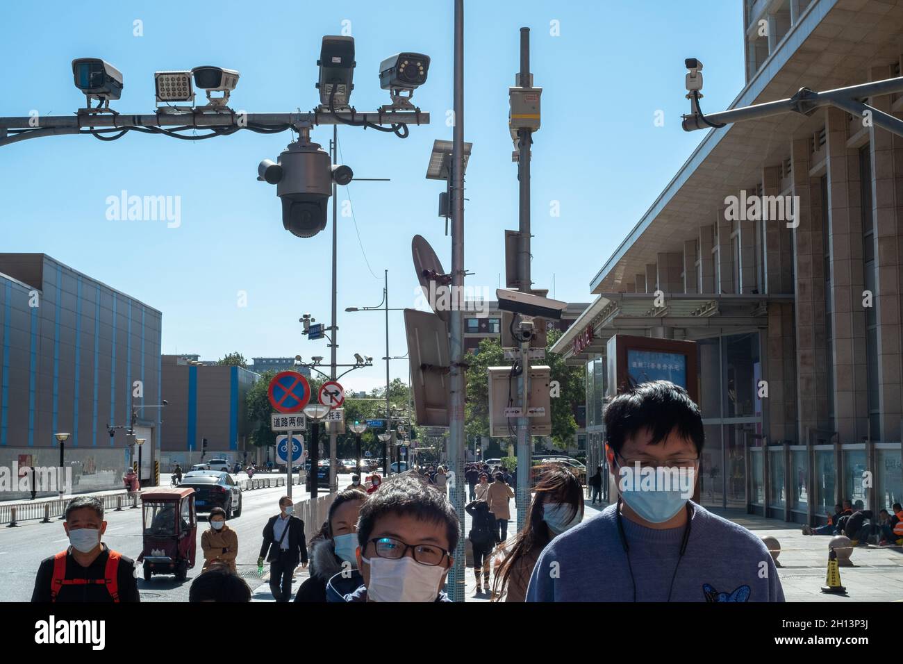 Pedestrians walk below CCTV cameras in Wangfujing Street in Beijing, China. 16-Oct-2021 Stock Photo