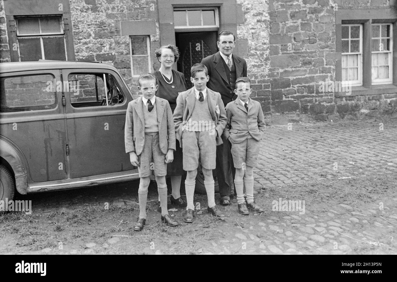 A 1950s vintage photograph showing a family of  5, including three young boys, standing by a car. Photo taken in England. Stock Photo