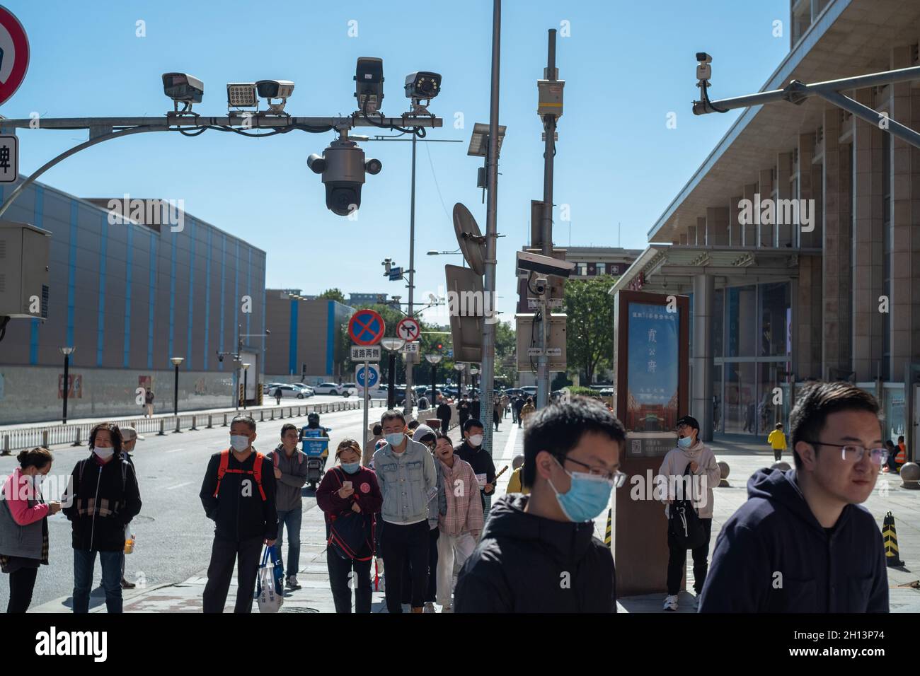 Pedestrians walk below CCTV cameras in Wangfujing Street in Beijing, China. 16-Oct-2021 Stock Photo