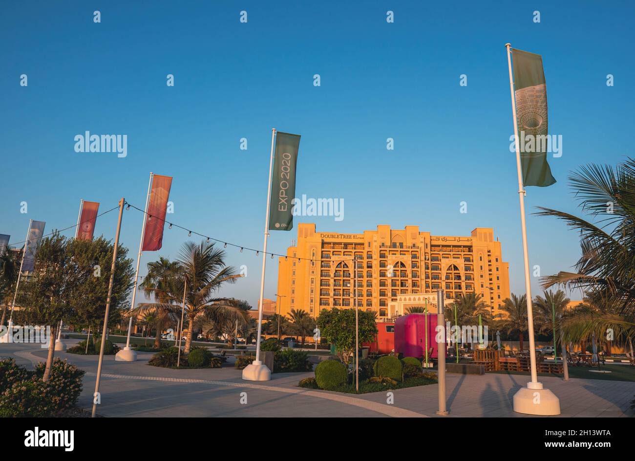 'Ras al Khaimah, UAE, 10.15.2021 - 'Orange and green flags for Expo 2020 flag outside Hilton Hotel on blue sky for global event in Dubai, United Arab Stock Photo