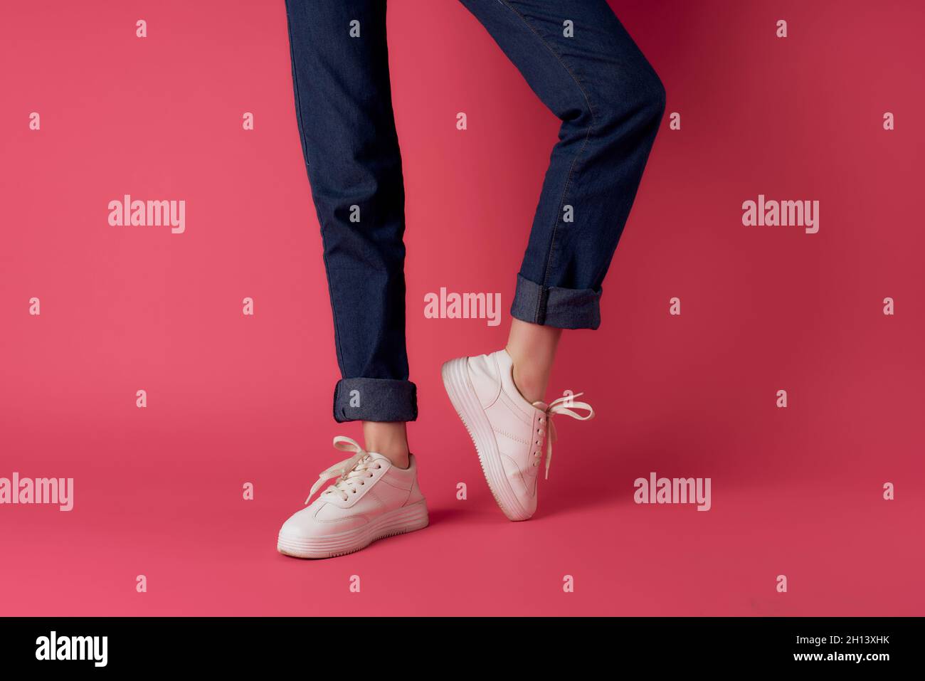 woman in white sneakers legs pink background posing Stock Photo - Alamy