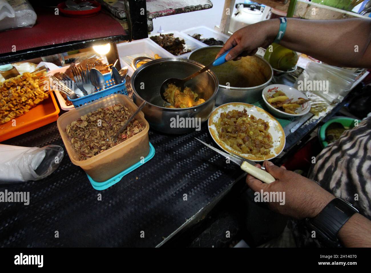 Karawang, Indonesia. 15th Oct, 2021. Endi, 39, he is one of the sons-in-law of the owner of Soto Tangkar stall Mang Nean who has been selling since 1980, is preparing food for consumers at the legendary food stall Soto Tangkar typical of Karawang on Jalan Dewi Sartika, West Karawang, Karawang, West Java, Indonesia. This soto dish uses beef ribs and beef leg veins seasoned with turmeric and chili. It tastes savory and slightly sweet. Interestingly, this delicious dish is cooked traditionally. Almost all ingredients are steamed in a pot over coals of firewood. The growth of micro, small and medi Stock Photo