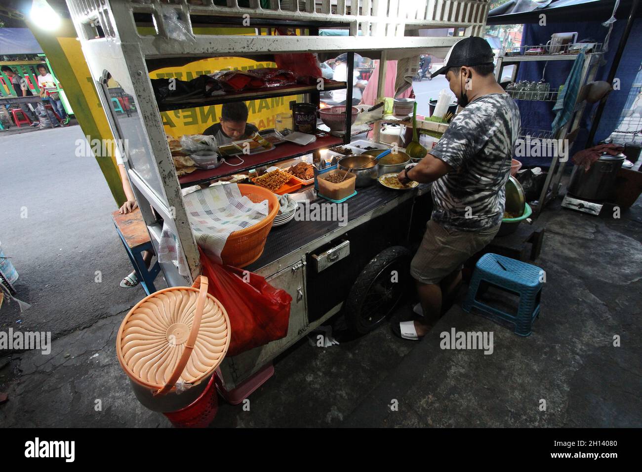 Karawang, Indonesia. 15th Oct, 2021. Endi, 39, he is one of the sons-in-law of the owner of Soto Tangkar stall Mang Nean who has been selling since 1980, is preparing food for consumers at the legendary food stall Soto Tangkar typical of Karawang on Jalan Dewi Sartika, West Karawang, Karawang, West Java, Indonesia. This soto dish uses beef ribs and beef leg veins seasoned with turmeric and chili. It tastes savory and slightly sweet. Interestingly, this delicious dish is cooked traditionally. Almost all ingredients are steamed in a pot over coals of firewood. The growth of micro, small and medi Stock Photo