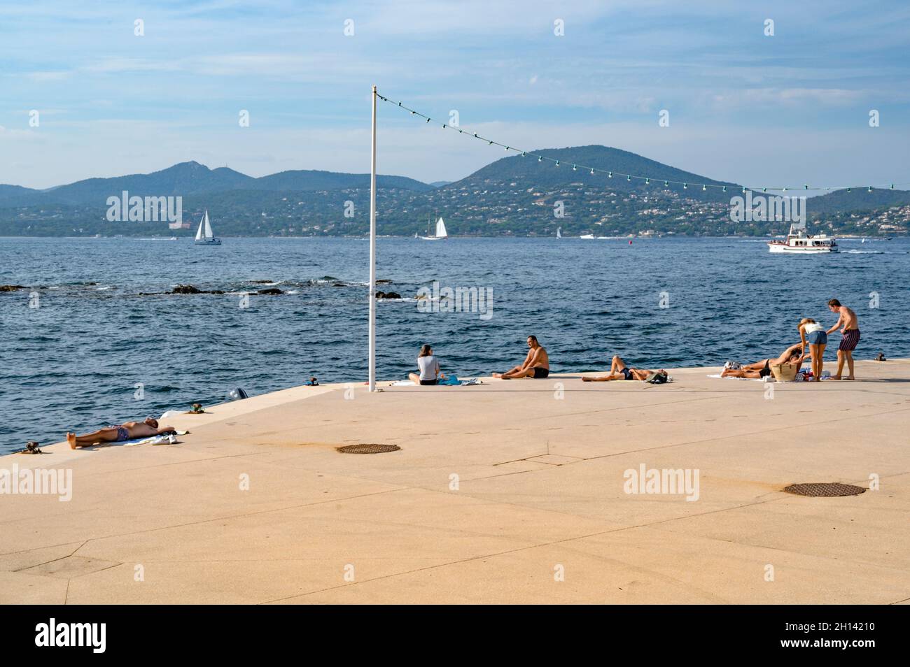 People sunbathing and enjoying the view across the bay of Saint-Tropez, France Stock Photo