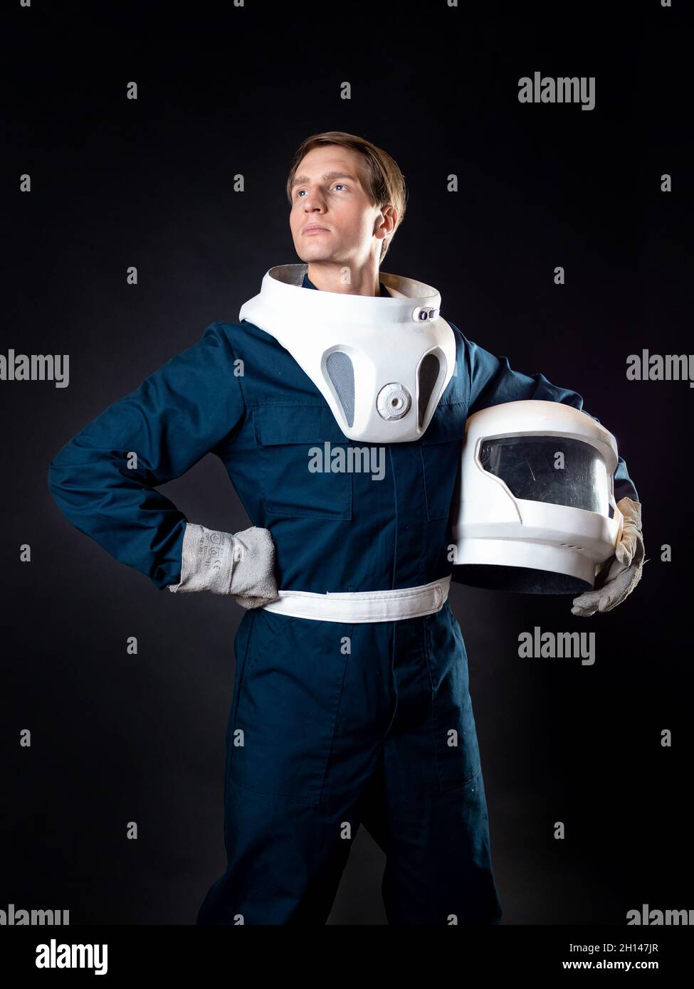 An astronaut or a space tourist. A young man in a spacesuit holds a helmet in his hands and smiles while waiting for takeoff Stock Photo