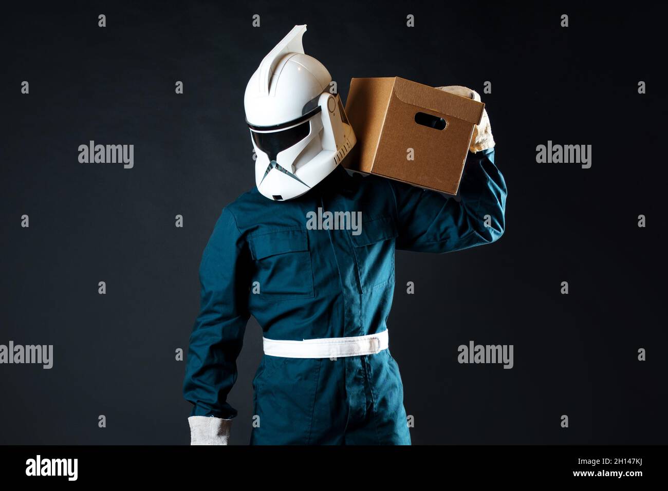 A space loader, a courier of the future delivered your parcel. A man in overalls and a helmet with a cardboard box in his hands Stock Photo