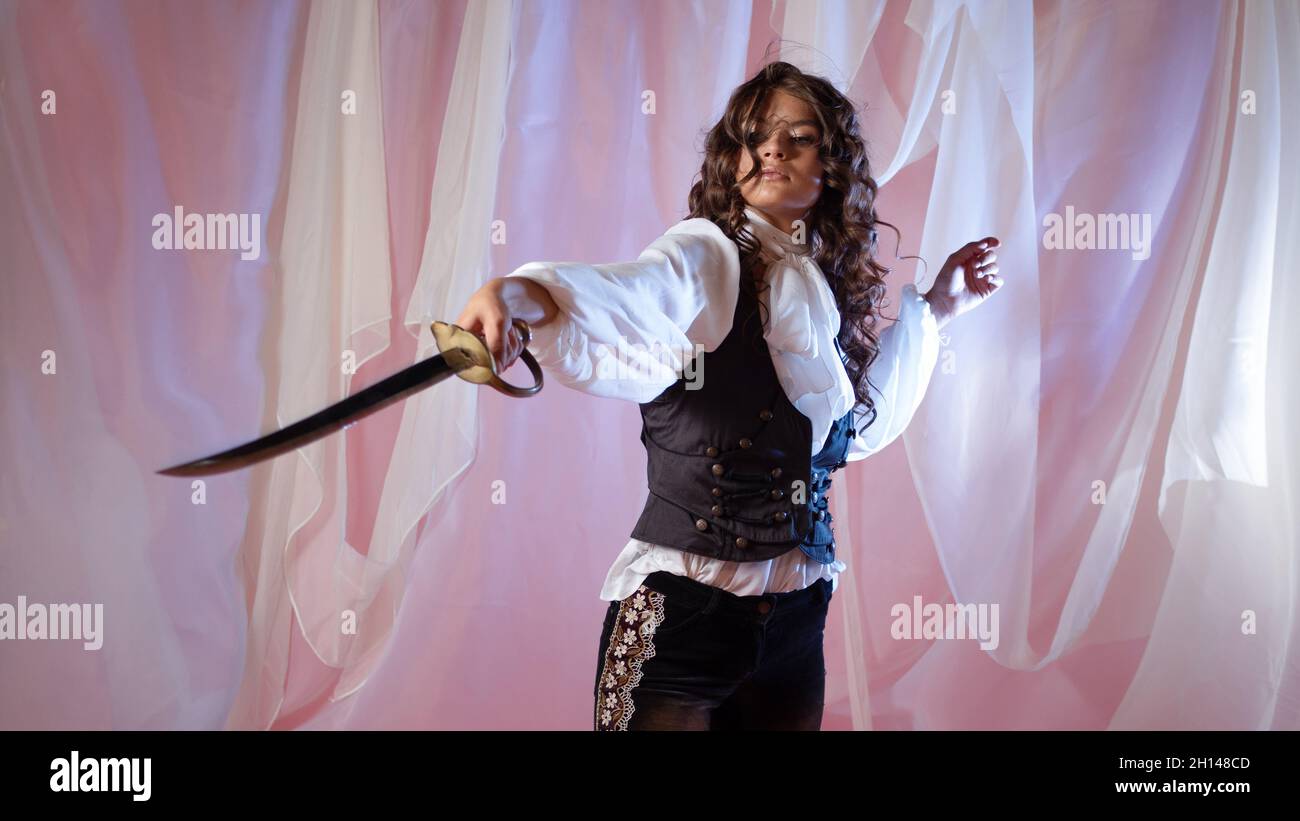 A pirate and an adventurer, the heroine of a fantasy story about pirates and adventures. Beautiful brunette with a sword fencing with an opponent, sai Stock Photo