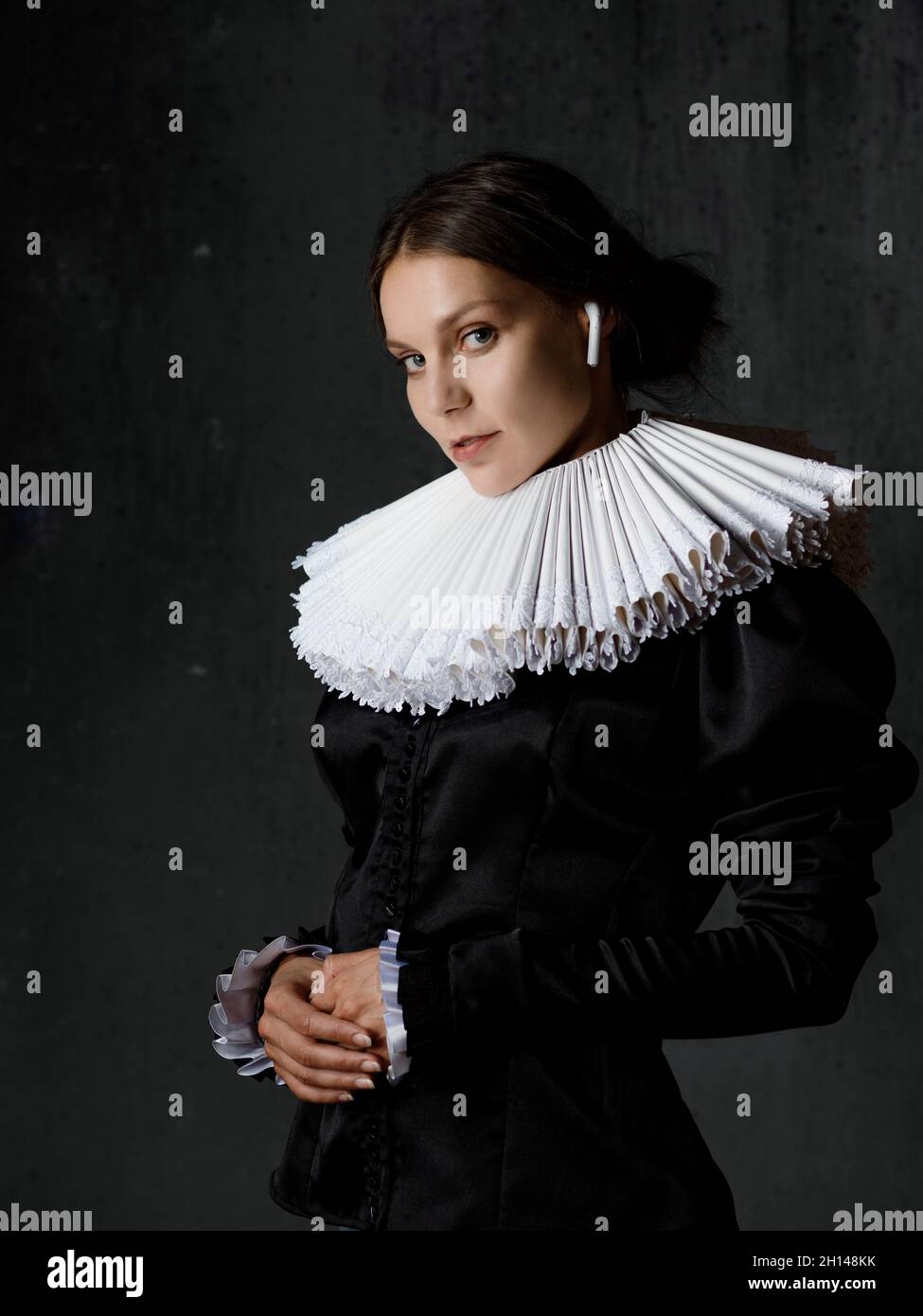 A noble lady in an old round collar enjoys music using modern