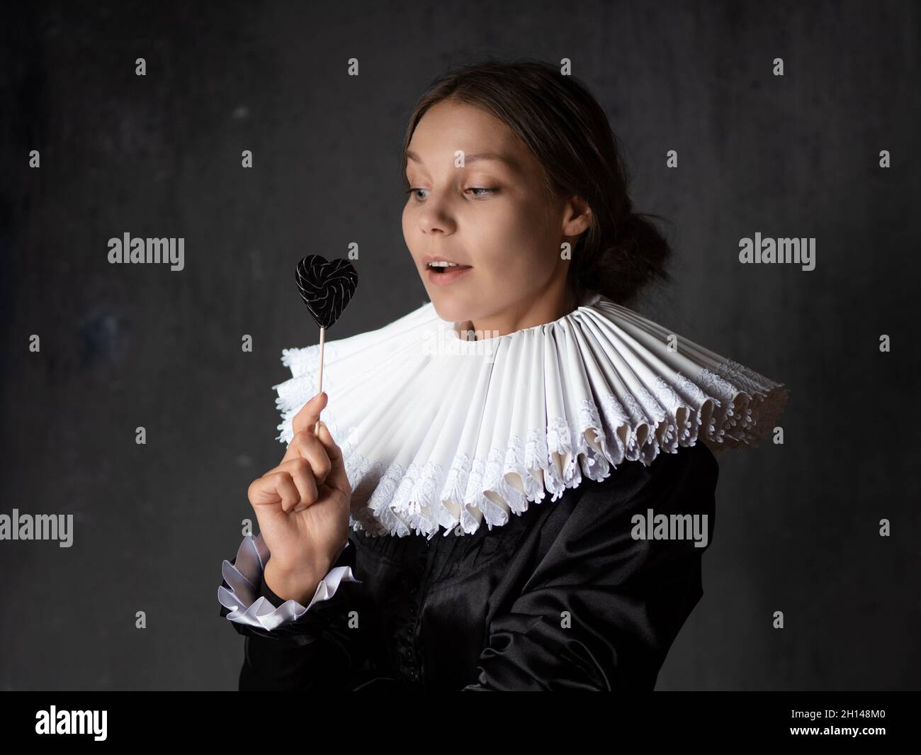 A noble lady in an old round collar with a lollipop in her hands. Portrait in the Renaissance style with elements of modernity. Stock Photo