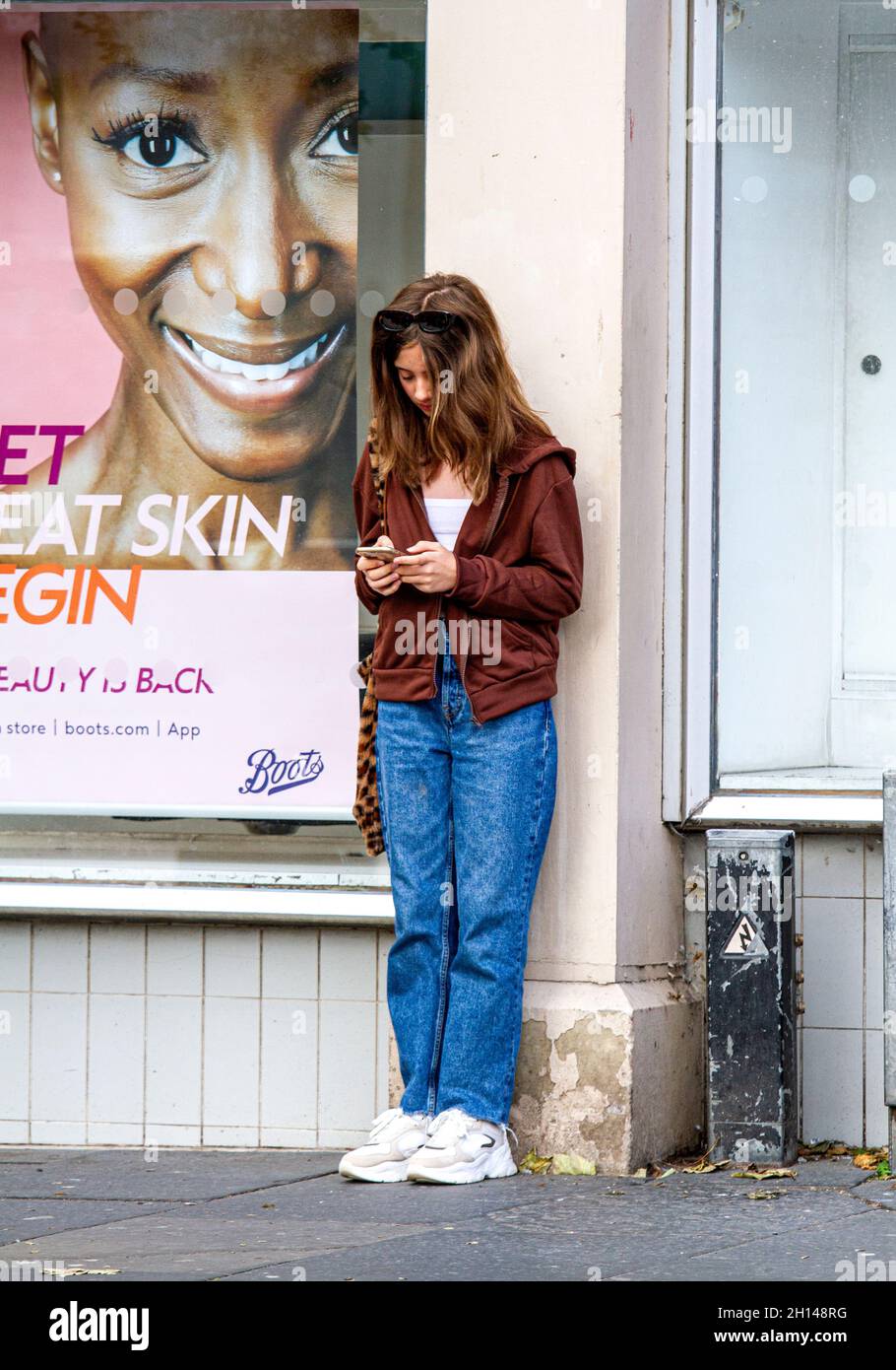 Dundee, Tayside, Scotland, UK. 16th Oct, 2021. UK Weather: A quite cool and bright Autumn day with sunny spells across North East Scotland, temperatures reaching 10°C. An attractive young woman is spending the day out enjoying the cool bright Autumn weather texting messages on her mobile phone whilst shopping in Dundee city centre. Credit: Dundee Photographics/Alamy Live News Stock Photo