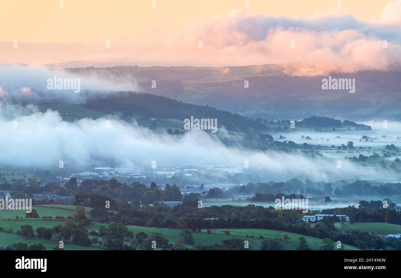 Skipton and the Aire Valley are covered in low hanging mist and clouds on a crisp autumn morning viewed from Sharp Haw in the Yorkshire Dales. Stock Photo