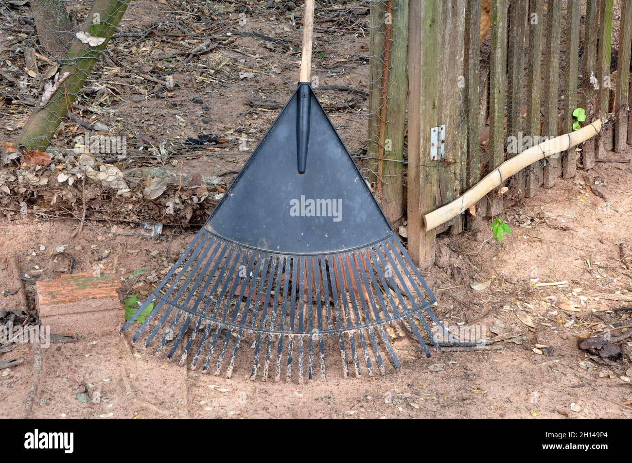 Rake, iron instrument used for clearing land in farms and farms, with a wooden handle, earthen floor in the background, wire fence and wood, Brazil, S Stock Photo