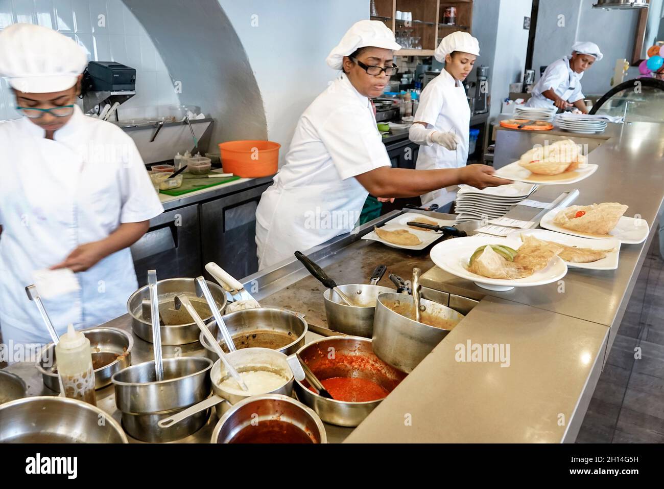 Cartagena Colombia,Crepes & Waffles restaurant,inside interior open kitchen cook chef,Black female women working plating food preparing order Stock Photo