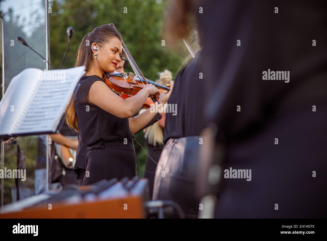 Charming female violinist playing in orchestra on the street Stock Photo