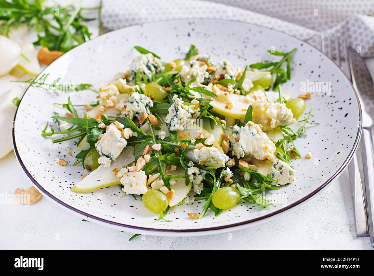 Salad of pear, blue cheese, grape, arugula and nuts with spicy dressing