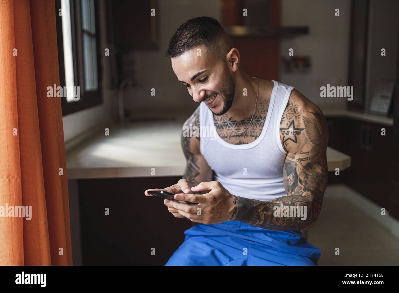 Young fit Caucasian tattooed male using his smartphone Stock Photo