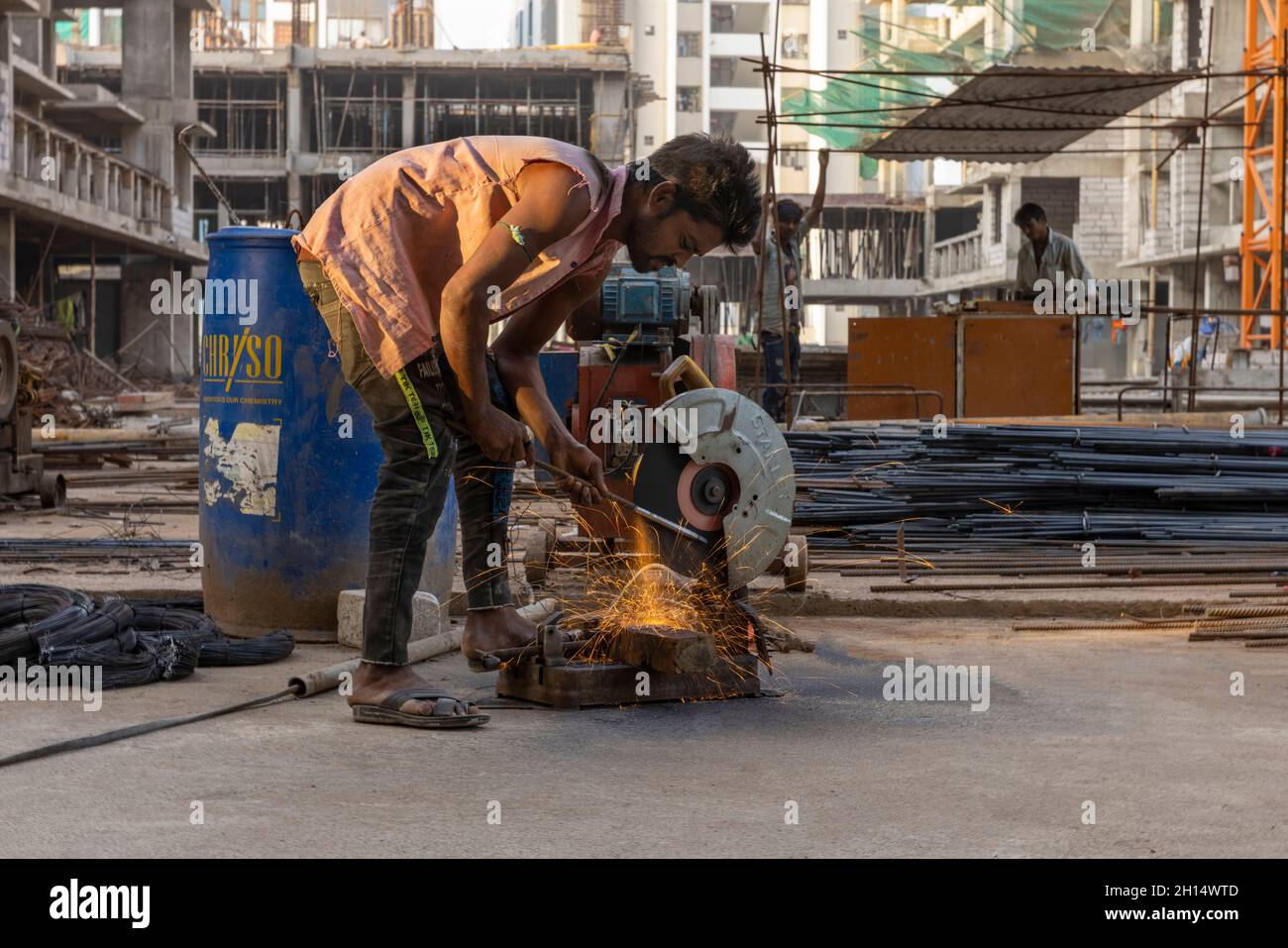 A daily wage labourer cutting metal on a construction site Stock Photo