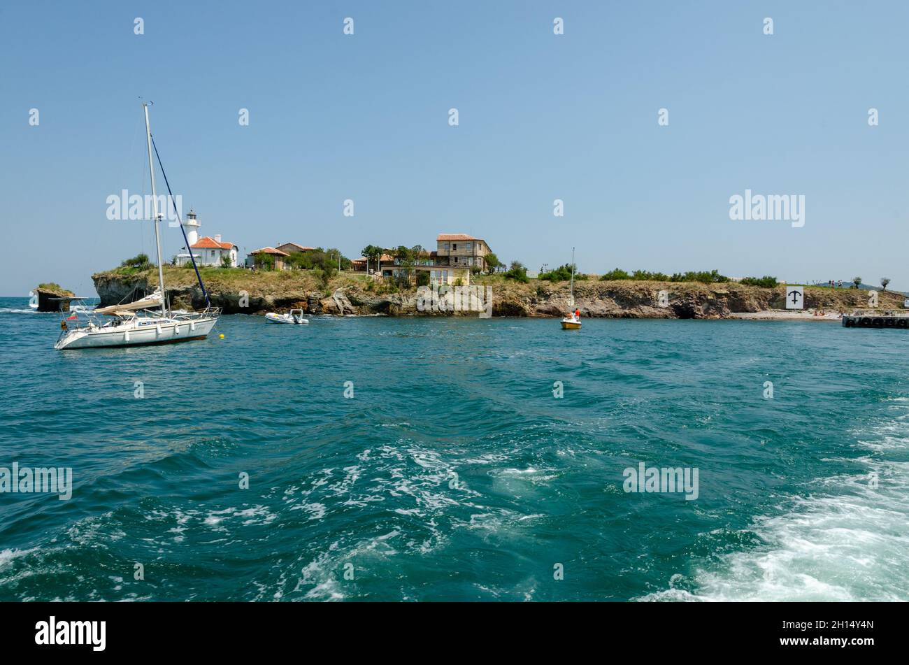 Saint Anastasia Island in Burgas bay, Black Sea, Bulgaria. Lighthouse tower and old wooden buildings on rocky coast. Stock Photo