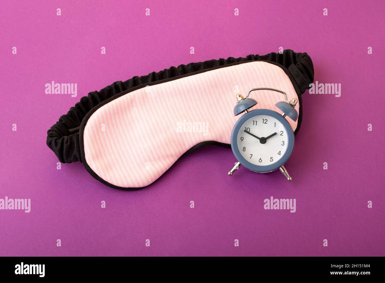 Mask for sleep and alarm clock near it.Circadian rhythms concept Stock