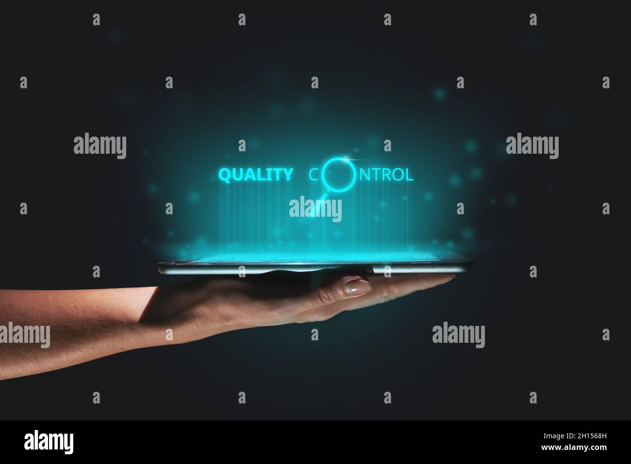 Quality control concept in production and business. A hand holds a tablet with a hologram above it. Stock Photo