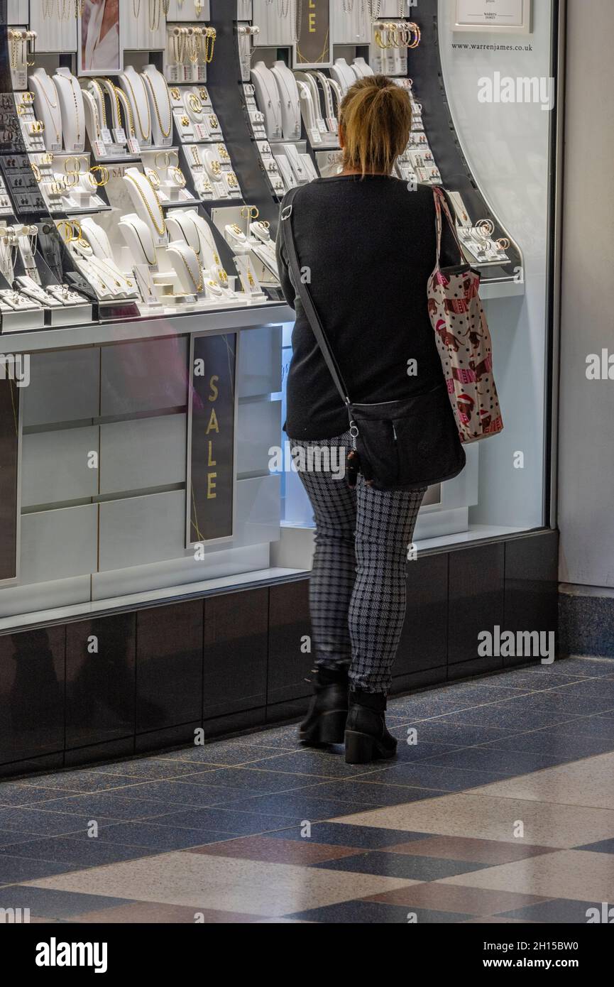 woman looking in the window of a jewellery shop. female shopping at a jewellers shop, lady looking at the display of jewellery in a high street store. Stock Photo