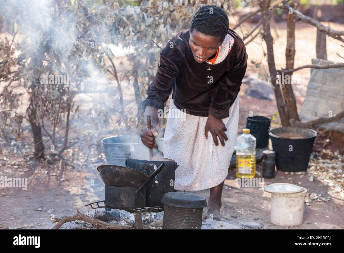 Outdoors kitchen, African woman cooking  pap and Setswa is a traditional African  food from Botswana made from boiled beef and tendons, Stock Photo