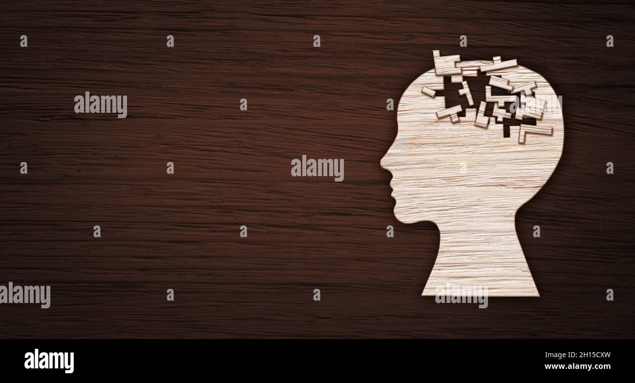 Mental health symbol. Human head silhouette with a puzzle cut out from wooden background. Stock Photo