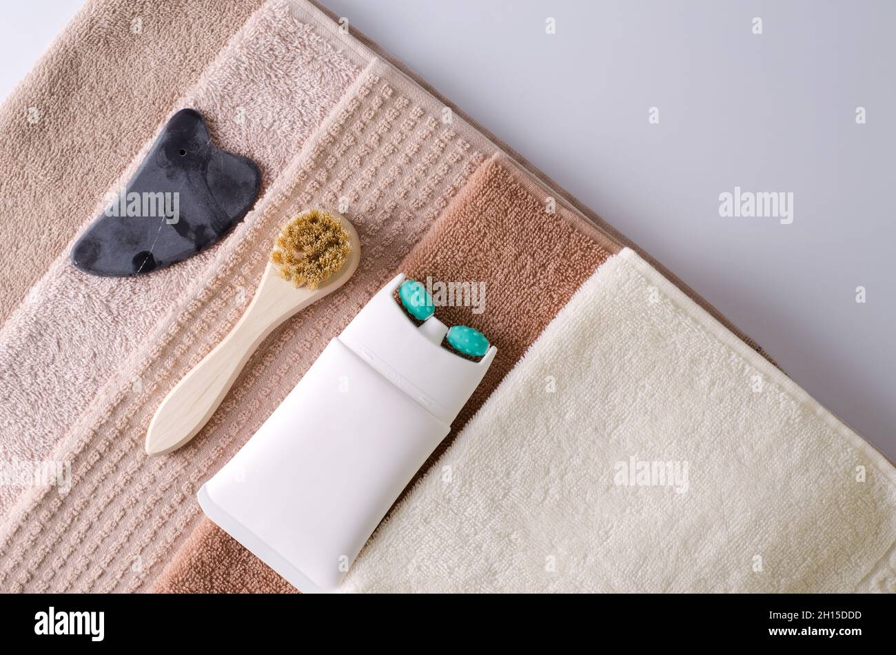 Lifting cream in a tube with a massage roller nozzle, brush made of natural bristles and gouache made of natural stone for a stack of towels, accessor Stock Photo