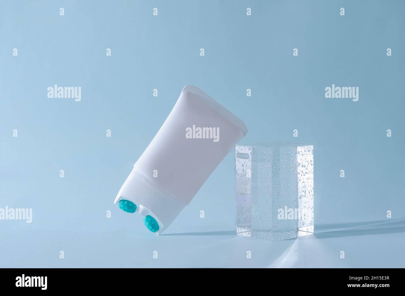 Cream lifting with massage nozzle in a white tube on a blue background with a podium of plexiglass Stock Photo