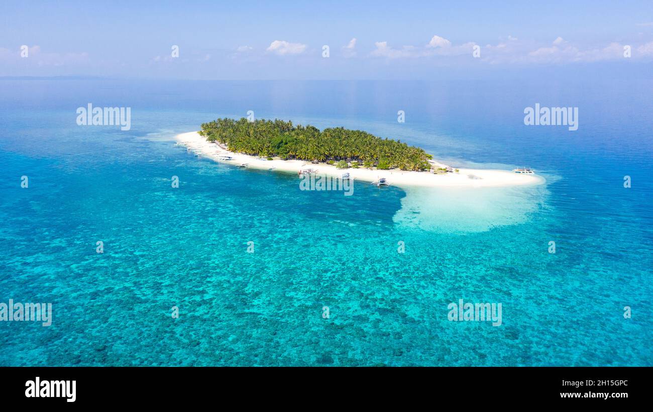 A tropical island in the distance. Island with a white sandy beach. Blue sea with coral reefs, top view. Digyo Island, Philippines. Stock Photo