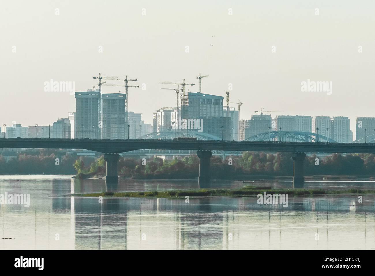 A large bridge to the city across the river against the backdrop of the cityscape and urban landscape architecture. Stock Photo