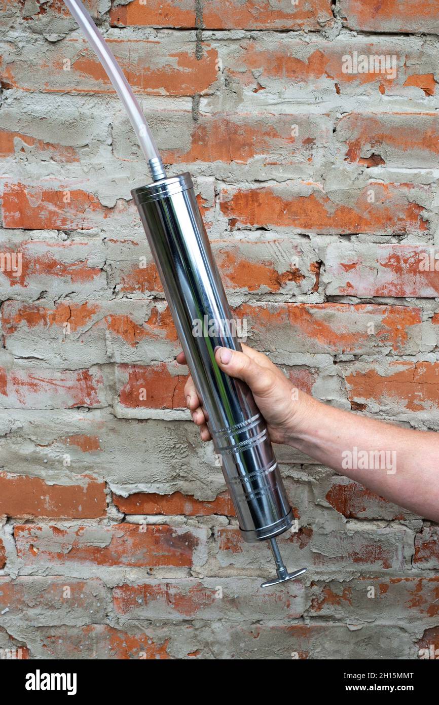 a metal syringe with a tube for filling engine oil into the engine in