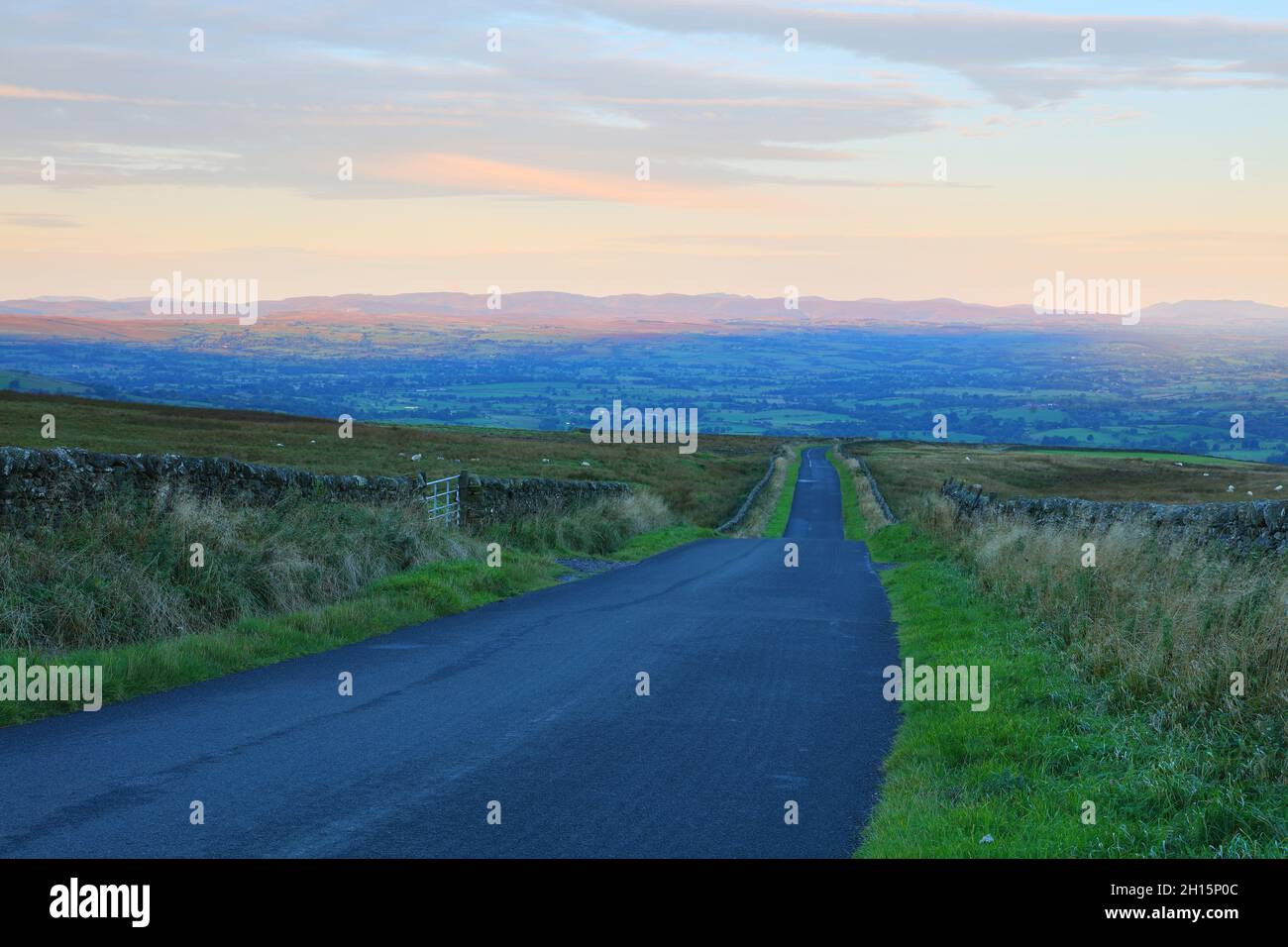 Lonely Road leading to the Eden Valley with the Lake District Mountains on the Horizon, Cumbria, England, UK. Stock Photo