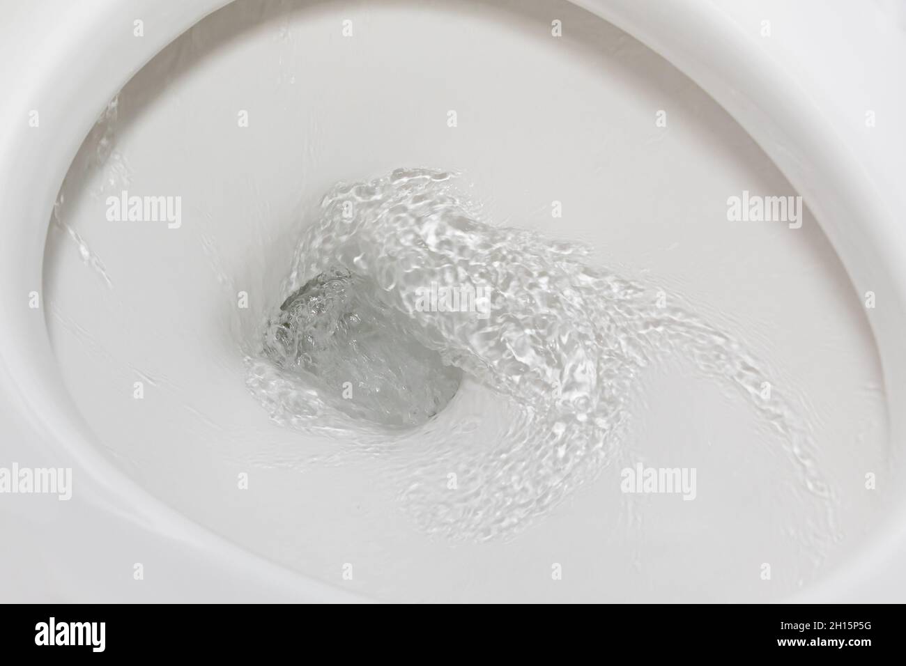 Motion blur of flushing water in toilet bowl. Plumbing, home repair and water conservation concept. Stock Photo