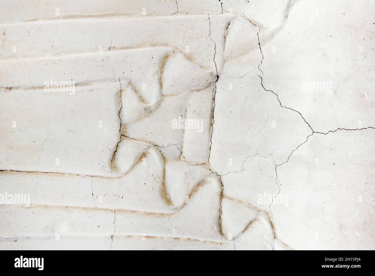 Close-up photo texture of worn and cracked marble wall with cloth ornament. Stock Photo