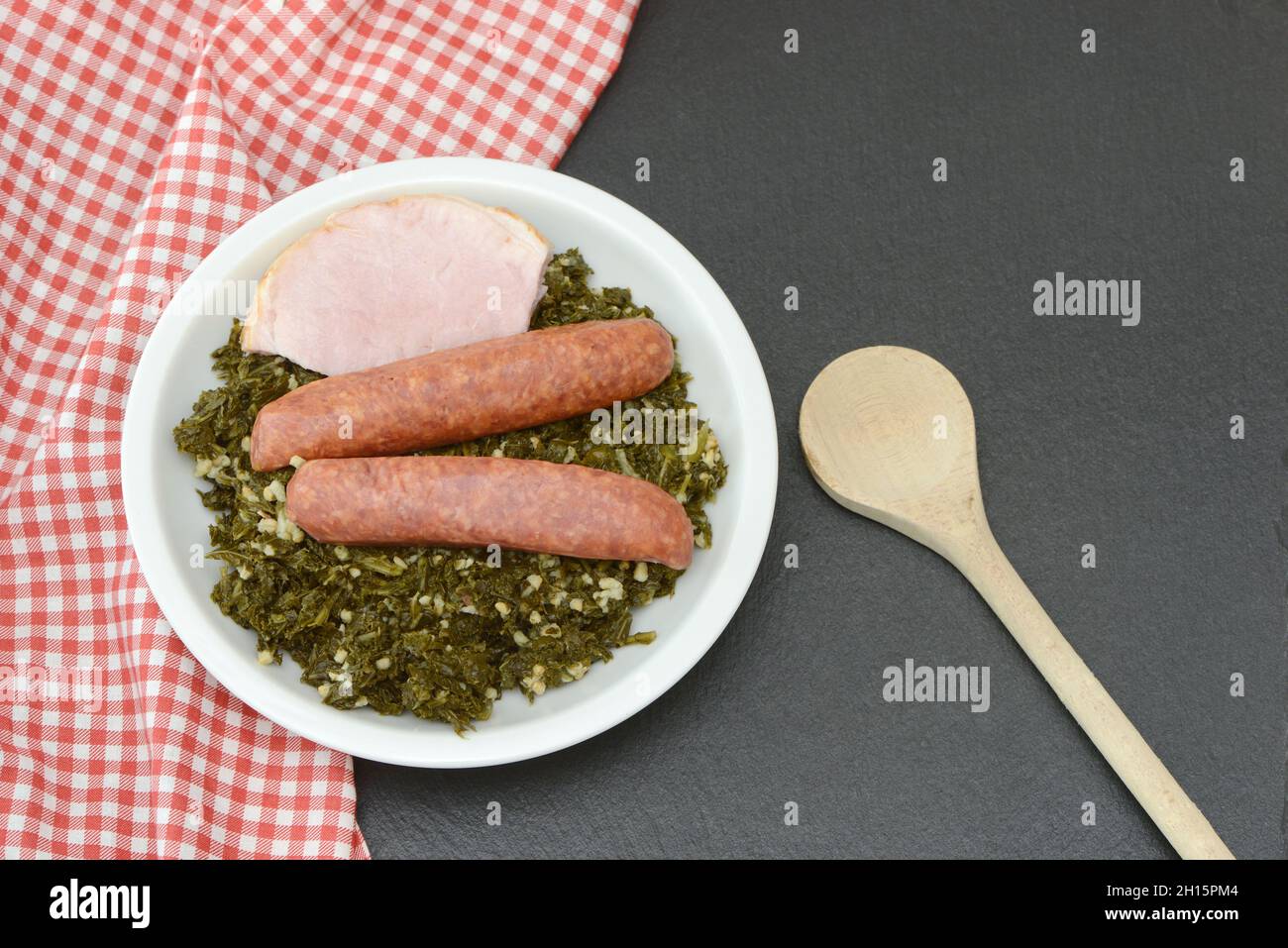 Fresh cooked kale with sausages on plate on black background Stock Photo