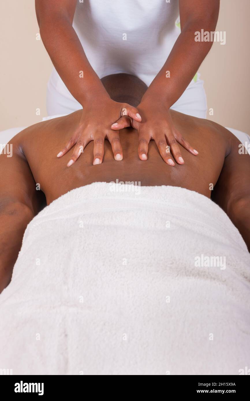 Massage therapy, hot stone massage, African man on the bed, getting a massage Stock Photo