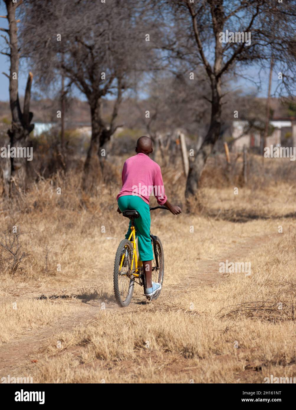 African Kid Riding A Bicycle On A Dirt Road In A Village In Botswana