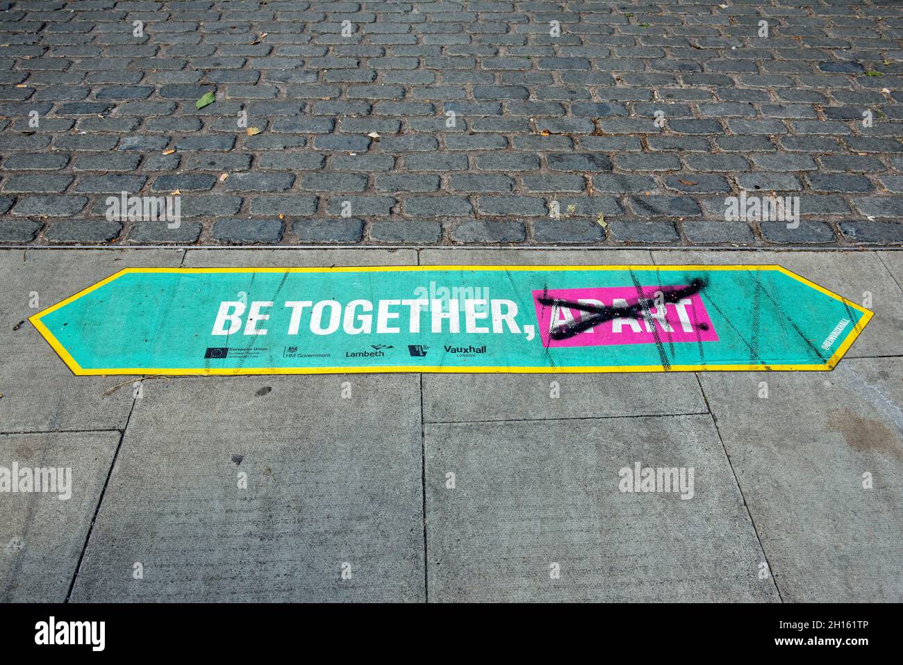 Be Together, Apart sign on pavement with apart crossed through.  Social distancing due to Covid 19 Stock Photo